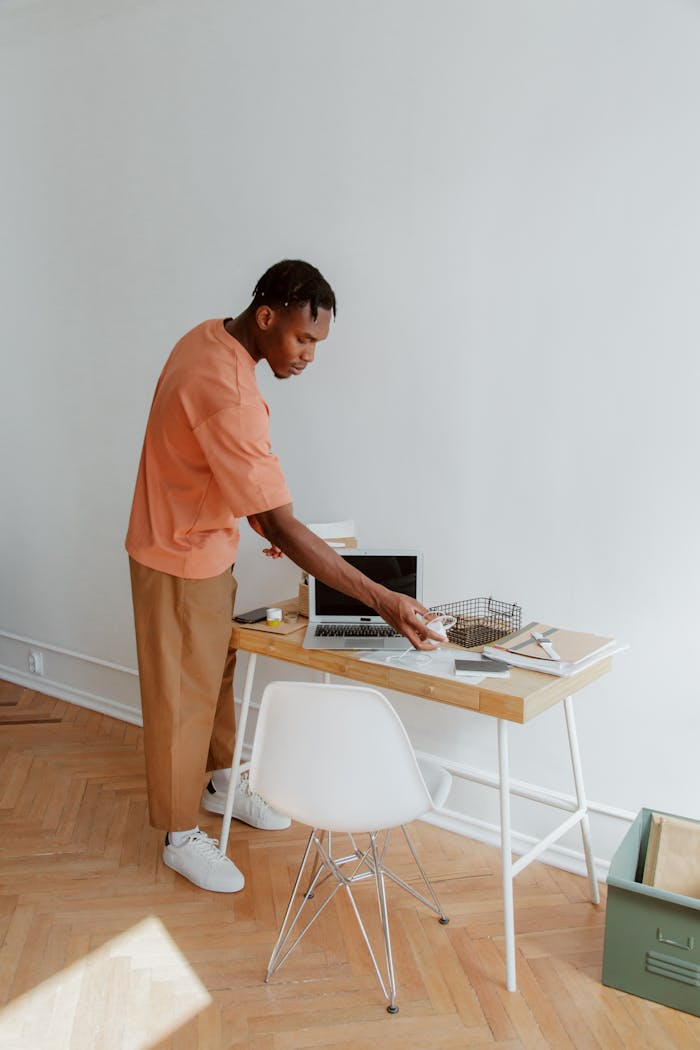 services-01 A man standing at a desk organizing papers and electronic devices in a modern office setting.